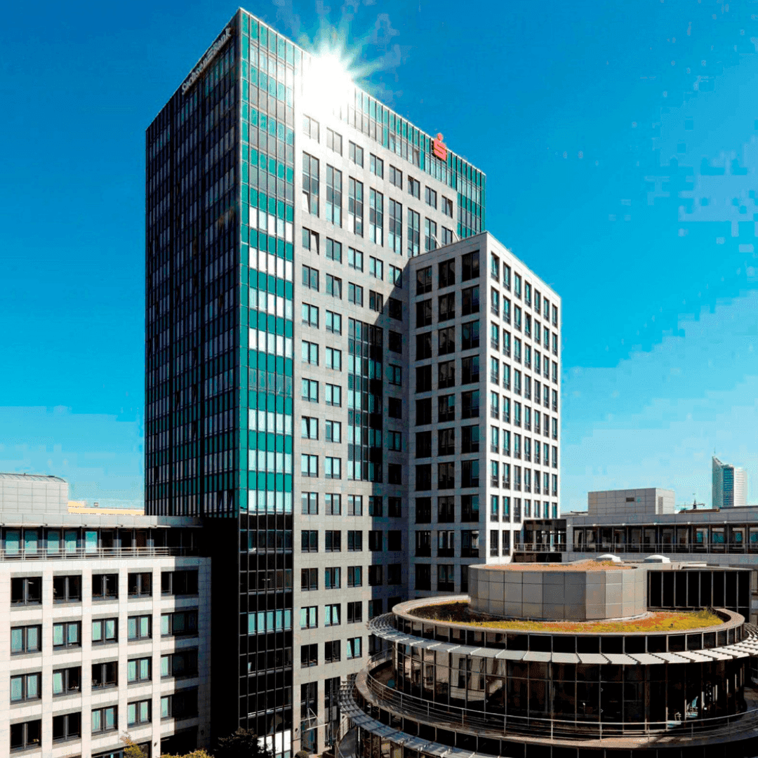 Modern, reflective office building under a bright, sunny sky with a starburst effect.