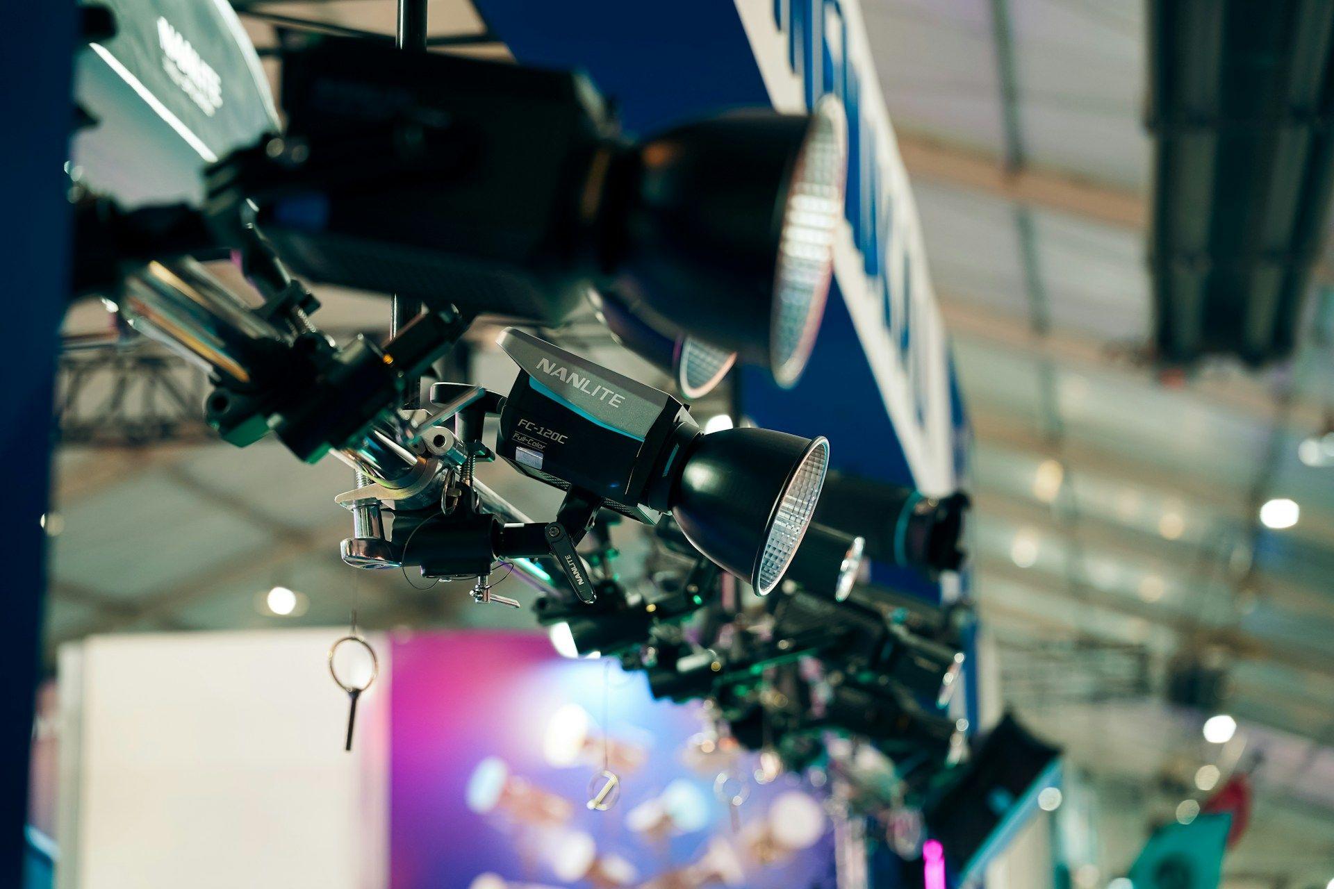 Row of professional stage lights hanging from a rigging structure above an event.